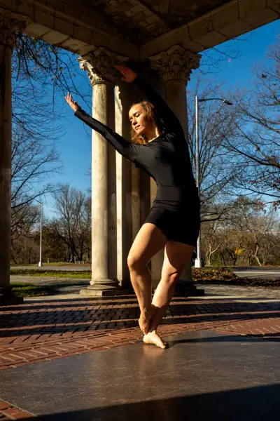 Lucy in a reaching pose at columns with beautiful natural light