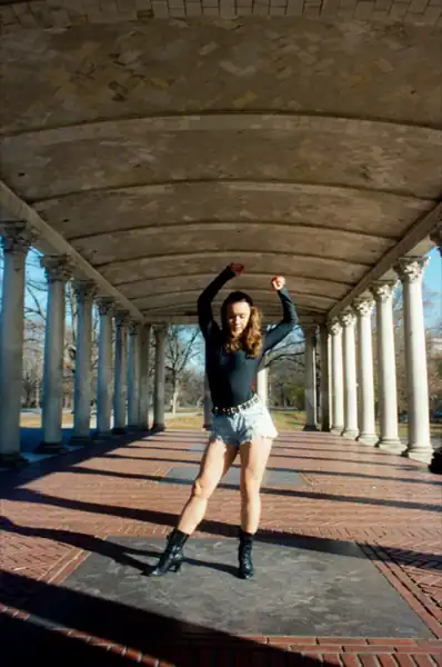 Lucy with arms raised in powerful stance wearing boots