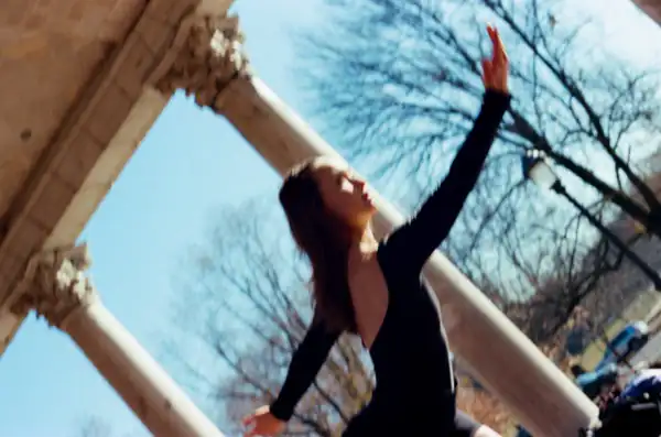 Lucy looking up at columns with open arms bathed in warm light